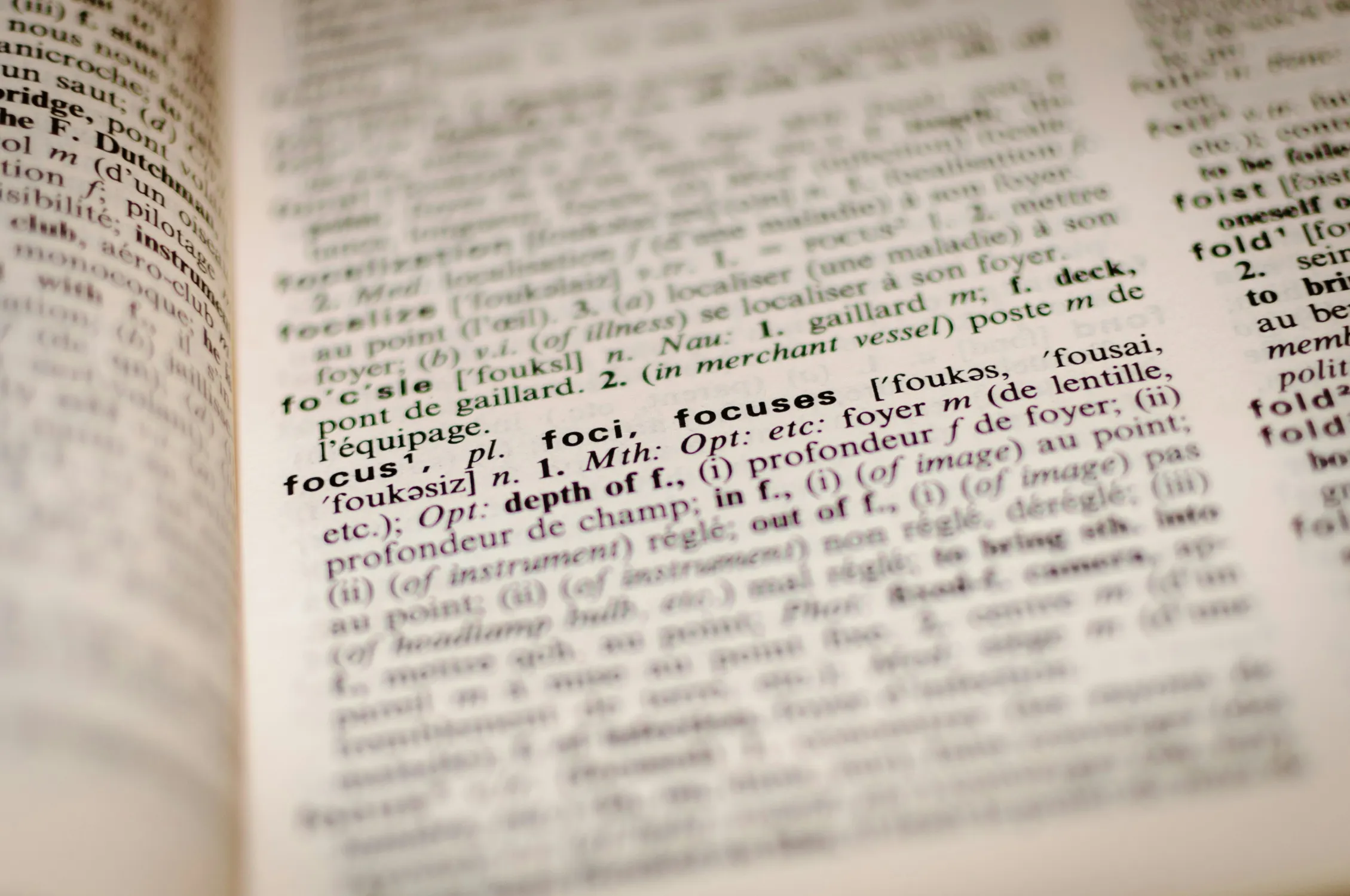 Imagen desenfocada de un diccionario definiendo la palabra "focus", enfoque en inglés